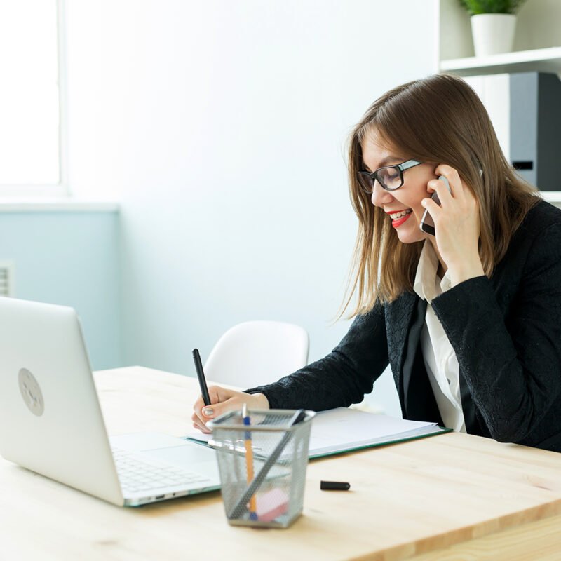 Business, realtor and people concept - Attractive woman in office talking on phone and make notes.